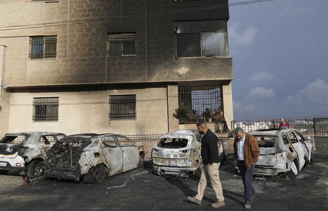 Palästinenser inspizieren Fahrzeuge, die von gewalttätigen israelischen Siedlern bei einem Angriff  am Rande der Stadt al-Bireh im Westjordanland in Brand gesetzt wurden.<span class='image-autor'>Foto: dpa/Nasser Nasser</span>