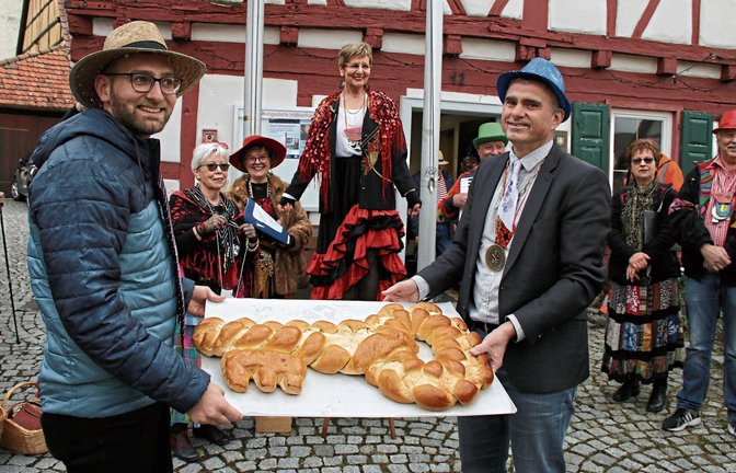 Ortsvorsteher Valentin Stuber (links) und Bürgermeister Holger Albrich überreichen den Zigeunerinnen den Rathausschlüssel in Häfnerhaslach – in Form eines Hefezopfes. Fotos: Bögel