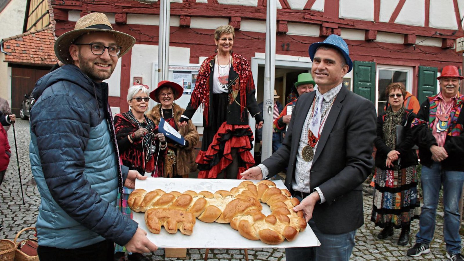 Ortsvorsteher Valentin Stuber (links) und Bürgermeister Holger Albrich überreichen den Zigeunerinnen den Rathausschlüssel in Häfnerhaslach – in Form eines Hefezopfes. Fotos: Bögel