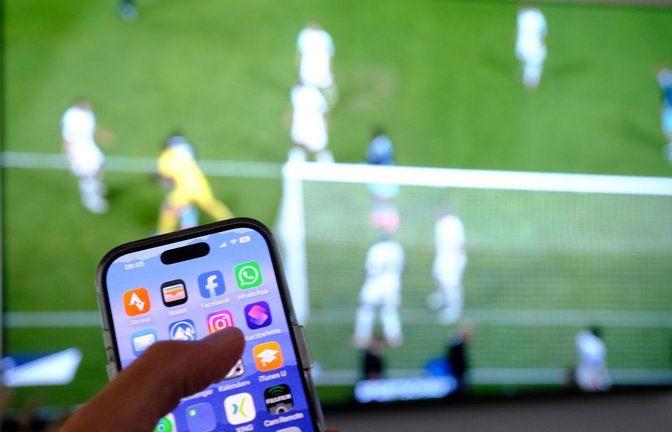 Nebenbei mal daddeln: Während das Fußballspiel läuft, schauen viele Zuschauer nebenbei aufs Handy. (Symbolbild)<span class='image-autor'>Foto: Bernd Weißbrod/dpa</span>