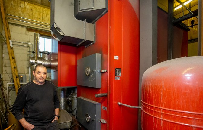 Jürgen Laub vor dem Heizkessel. Über eine Schnecke landen die Holzhackschnitzel automatisch in der Brennkammer. Das Wasser für die Fernwärme wird auf 78 Grad erhitzt. 76 Grad liegen beim Kunden an der Übergabestation am Hausanschluss an, so Laub.