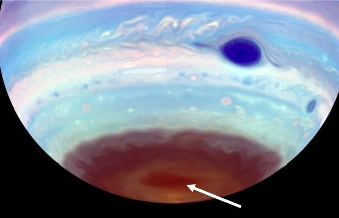 An den Polen des Jupiter haben Astronomen nur im UV-Licht sichtbare dunkle Ovale entdeckt – erdgroße, magnetisch angetriebene Tornados (Pfeil). Der Große Rote Fleck erscheint in dieser kolorierten UV-Aufnahme dunkelblau.<span class='image-autor'>Foto: © Troy Tsubota and Michael Wong/UC Berkeley</span>