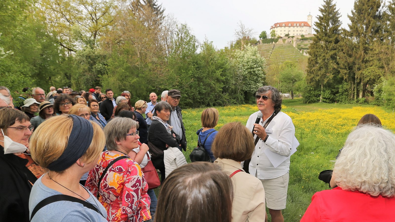 Planer Johann Senner (mit Mikrofon) führt die Gruppe durch die Köpfwiesen, wo er vor der Kulisse von Schloss Kaltenstein immer wieder Biotope erläutert, die in die Gartenschau einbezogen werden könnten. Fotos: Küppers