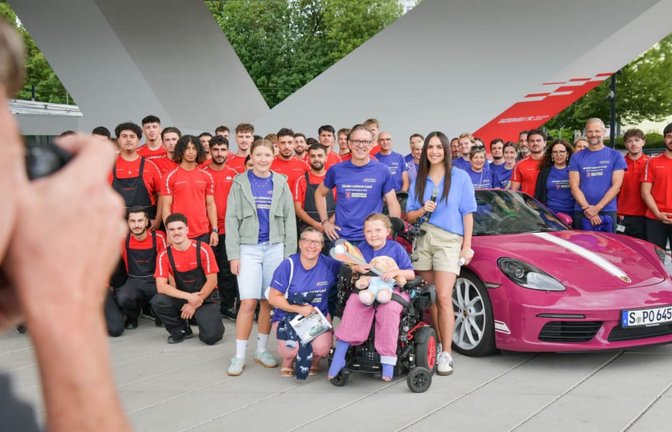 Bitte lächeln: „Starter-Kind“ Mira mit Mitarbeitern und Auszubildenden von Porsche und Porsche-Öffentlichkeitschef Florian Launer (Mitte) vor der Abfahrt des Benefiz-Konvois am Porschemuseum. Der Sportwagenhersteller unterstützt die Aktion des Bundesverbands Kinderhospiz e.V.<span class='image-autor'>Lichtgut/Max Kovalenko</span>