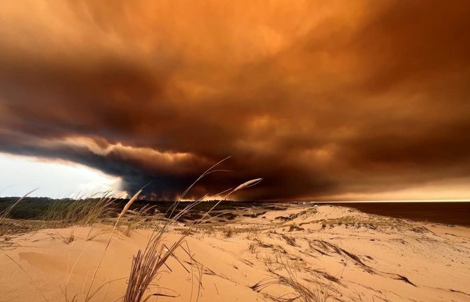 Rauchwolken von den Waldbränden südöstlich des Badeortes Lacanau-Ocean (hinten, r) verdunkeln den Himmel, während sie über die Dünen am Nordstrand hinwegziehen.<span class='image-autor'>Jan Athmann/dpa</span>