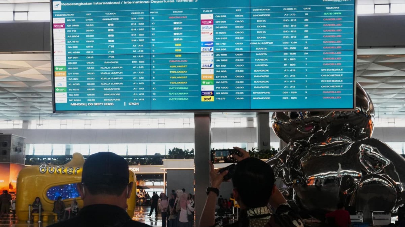 Reisende gehen am internationalen Flughafen Soekarno-Hatta an einer Informationstafel vorbei, auf der Flugausfälle angezeigt werden.Tatan Syuflana/AP/dpa