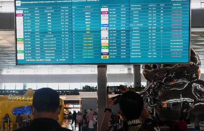 Reisende gehen am internationalen Flughafen Soekarno-Hatta an einer Informationstafel vorbei, auf der Flugausfälle angezeigt werden.<span class='image-autor'>Tatan Syuflana/AP/dpa</span>