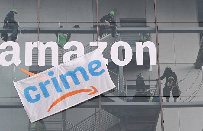 Greenpeace-Aktive hängen während der Rabattaktion Black Friday ein Plakat gegen die Ressourcenverschwendung des Online-Versandhändlers Amazon an dessen Gebäude in München auf.<span class='image-autor'>Foto: Felix Hörhager/dpa</span>
