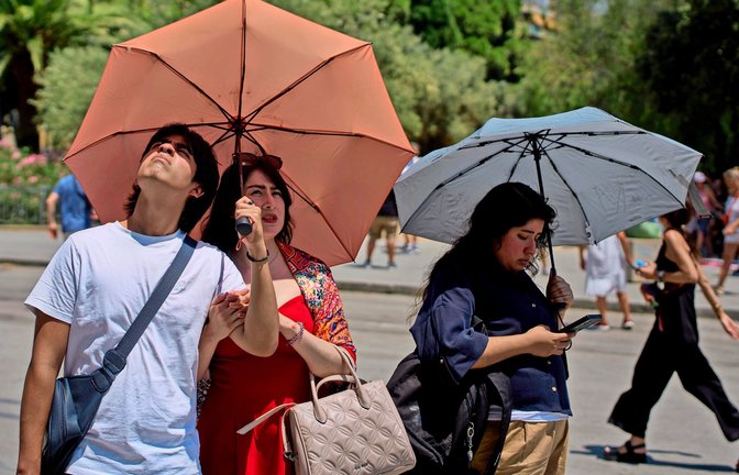Touristen schützen sich an einem heißen Tag  mit Regenschirmen vor der Sonne (Symbolfoto).<span class='image-autor'>Foto: Emilio Morenatti/AP/dpa/Emilio Morenatti</span>