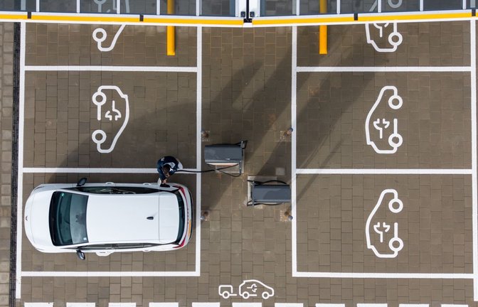 Ein Mann steht in einem Ladepark der EnBW Energie Baden-Württemberg AG und steckt ein Ladekabel in den Tankstutzen eines Elektroautos (Aufnahme mit einer Drohne). (zu dpa: «So beliebt sind Elektroautos im Südwesten»)<span class='image-autor'>Sebastian Kahnert/dpa</span>