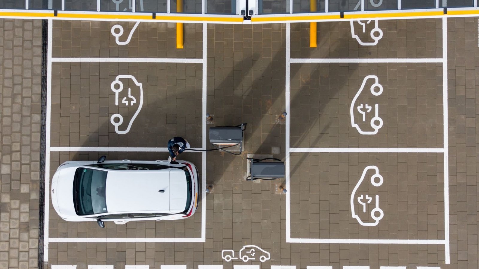 Ein Mann steht in einem Ladepark der EnBW Energie Baden-Württemberg AG und steckt ein Ladekabel in den Tankstutzen eines Elektroautos (Aufnahme mit einer Drohne). (zu dpa: «So beliebt sind Elektroautos im Südwesten»)Sebastian Kahnert/dpa