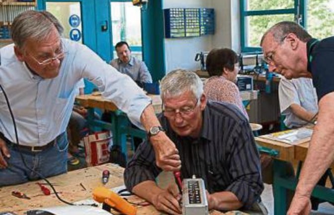 Reparateure und Kunden tüfteln am Gerät.  p