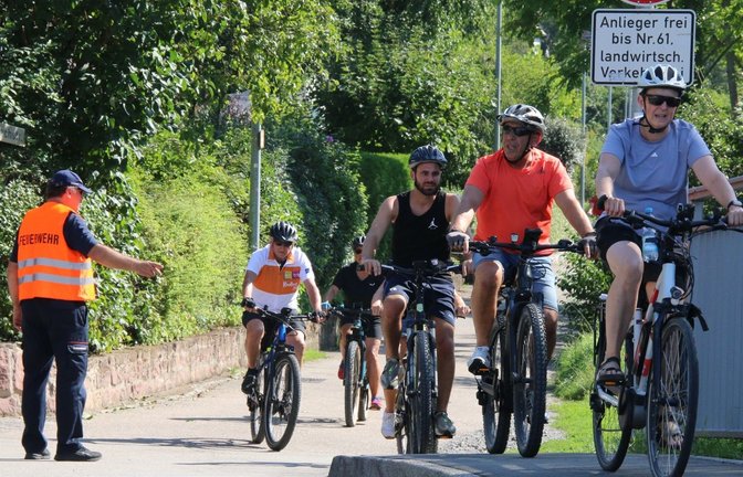 Ein Feuerwehrmann dirigiert die Radler bei Sachsenheim auf den Gehweg.