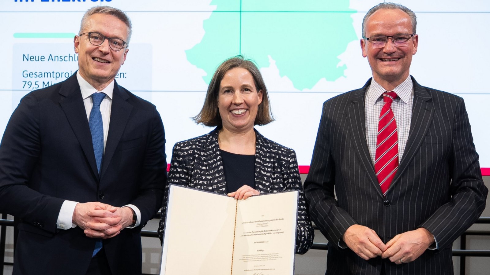 Übergabe in Berlin (von links): Bundesminister Karsten Wildberger überreicht den Förderbescheid für den Ausbau der Grauen Flecken an Hilde Neidhardt, Erste Landesbeamtin des Enzkreises. Das freut auch Staatsminister Gunther Krichbaum.  Foto: Bundesministerium für Digitales und Staatsmodernisierung