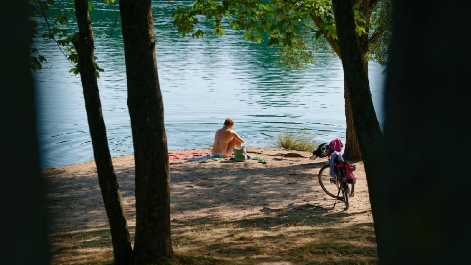 Eine Frau sitzt am Ufer des Vogelstangsee.Uwe Anspach/dpa Eine Frau sitzt am Ufer des Vogelstangsee.Uwe Anspach/dpa