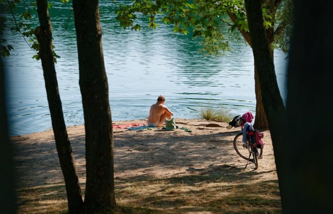 Eine Frau sitzt am Ufer des Vogelstangsee.<span class='image-autor'>Uwe Anspach/dpa</span>
