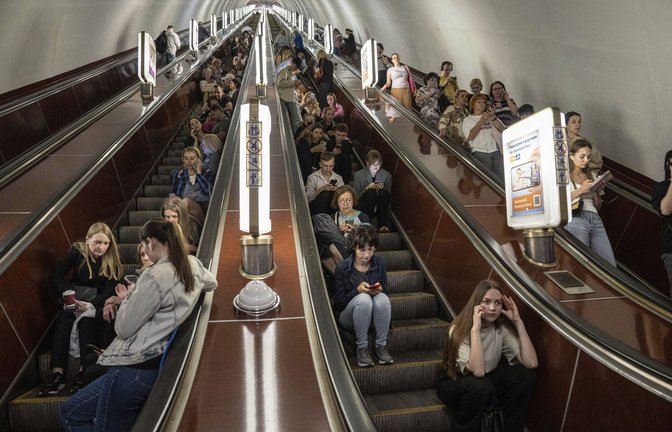 Menschen sitzen auf einer Rolltreppe, während sie in einer Metrostation der ukrainischen Hauptstadt Kiew Schutz vor russischen Raketen- und Drohnenangriffen suchen.<span class='image-autor'>Foto: dpa/Evgeniy Maloletka</span>