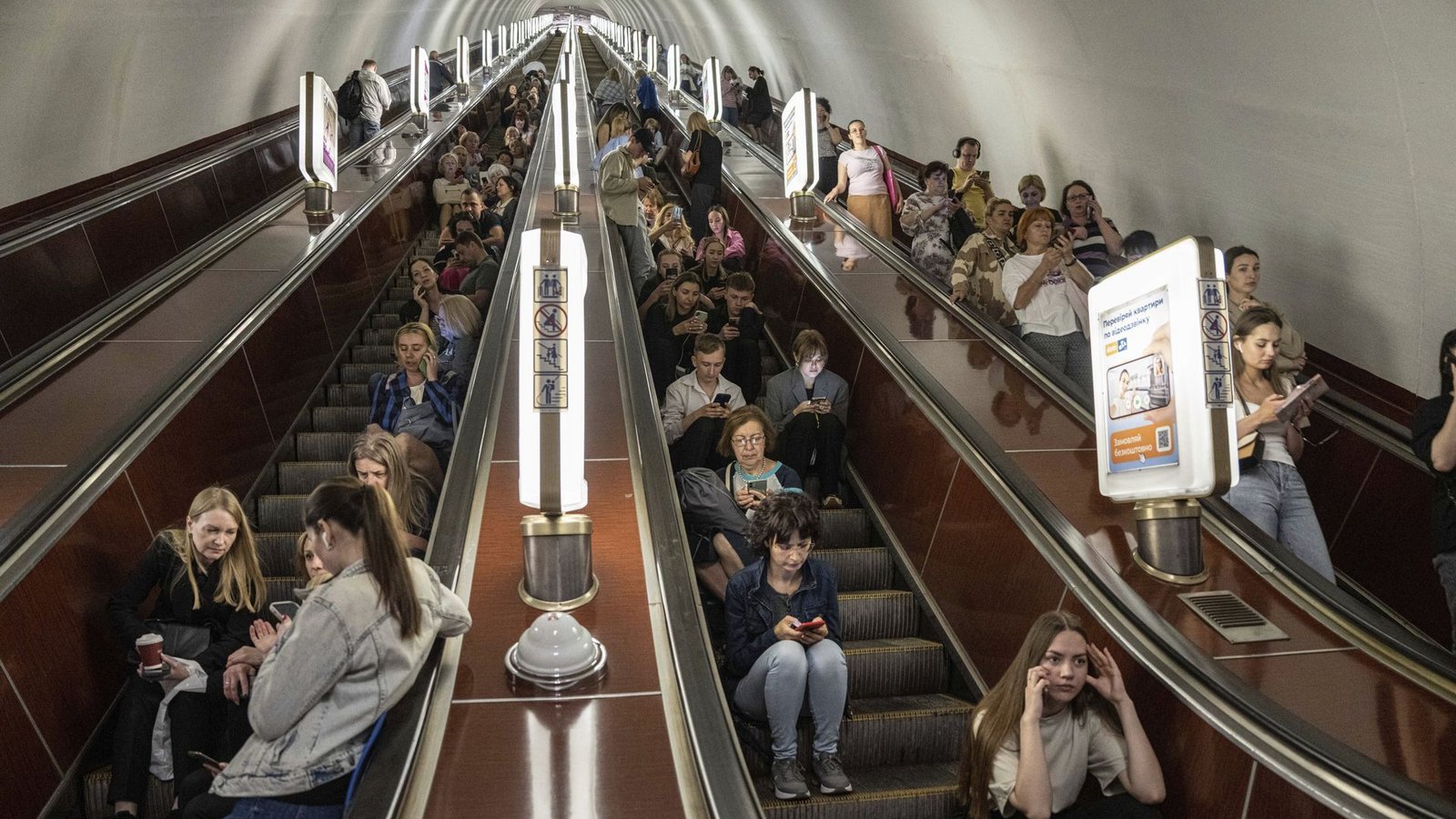 Menschen sitzen auf einer Rolltreppe, während sie in einer Metrostation der ukrainischen Hauptstadt Kiew Schutz vor russischen Raketen- und Drohnenangriffen suchen.Foto: dpa/Evgeniy Maloletka