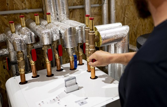 Ein Handwerker beim Installieren einer Wärmepumpe. Im Neubau setzt sich diese Heizungsform durch – im Bestand sind Hausbesitzer oft skeptisch.<span class='image-autor'>Foto: dpa/Fabian Sommer</span>