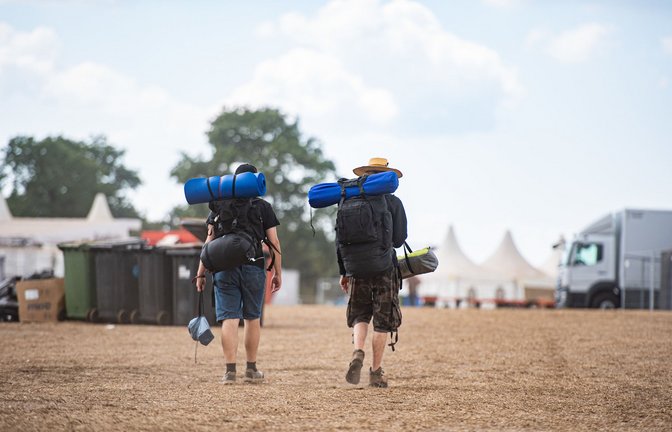 Zwei Festivalbesucher gehen mit ihrem Reisegepäck über das Wacken Open Air Festival.<span class='image-autor'>Foto: dpa/Daniel Reinhardt</span>