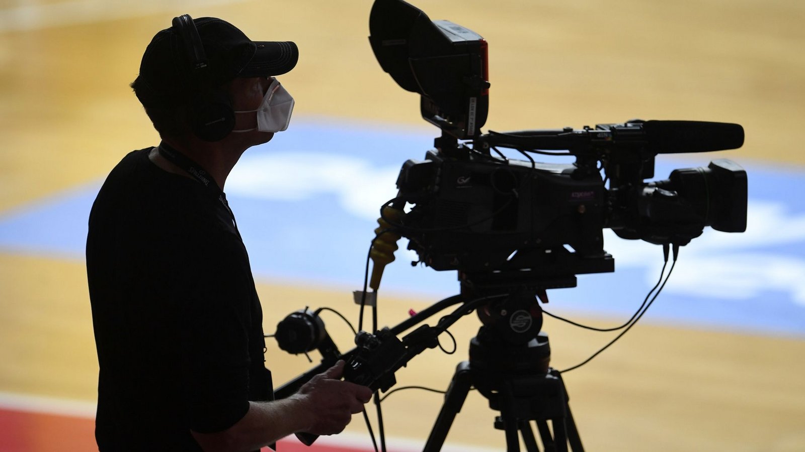 Ein Kameramann steht mit Mundschutz am Rand eines Basketballfeldes.Foto: Andreas Gebert/Reuters-Pool/dpa