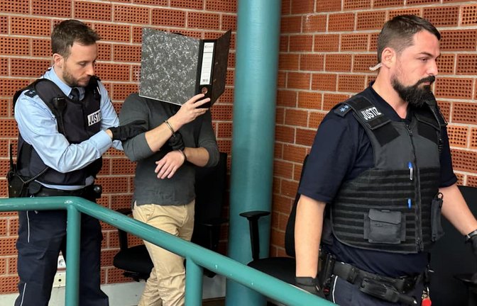 Der falsche Schönheitsarzt wird in Konstanz vor den Richter geführt. Sein Gesicht versteckt er vor den Kameras der Journalisten hinter einem Aktenordner.<span class='image-autor'>Cornelia Spitz</span>