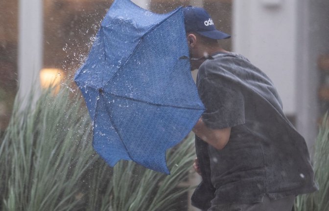 Ein Mann rennt in Stuttgart durch starken Regen und versucht, sich mit einem Regenschirm zu schützen. (zu dpa: «Regnerischer Tag: Wo sogar Gewitter und Sturmböen drohen»)<span class='image-autor'>Marijan Murat/dpa</span>