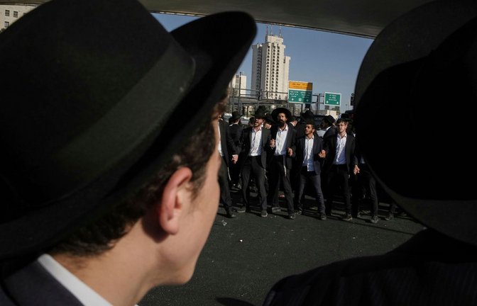 Ultraorthodoxe jüdische Männer blockieren eine Straße während einer Demonstration gegen die Rekrutierung von Soldaten (Archivfoto).<span class='image-autor'>Foto: Leo Correa/AP/dpa</span>
