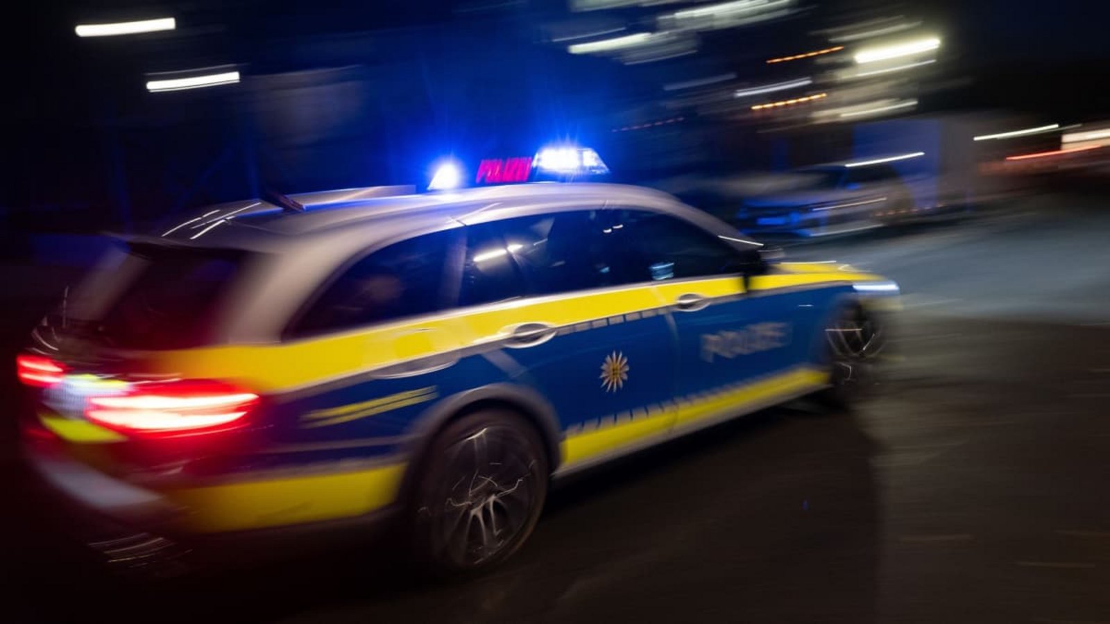 Ein Polizeifahrzeug fährt im Rahmen eines Fototermins mit Blaulicht an einem Gebäude vorbei (gestellte Szene, Langzeitblichtung mit Wischeffekt). (zu dpa: «Blutüberströmter Mann stoppt Auto nach Messerattacke»)Marijan Murat/dpa