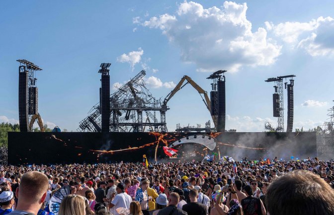 Vor der Kulisse der niedergebrannten Hauptbühne in Boom feiern die Festivalbesucher.<span class='image-autor'>Foto: AFP/MARIUS BURGELMAN</span>