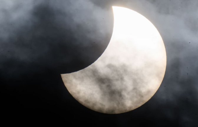 Eine partielle Sonnenfinsternis ist zwischen Wolken am Himmel zu sehen. (Aufnahme stammt aus Niedersachsen).<span class='image-autor'>Julian Stratenschulte/dpa</span>