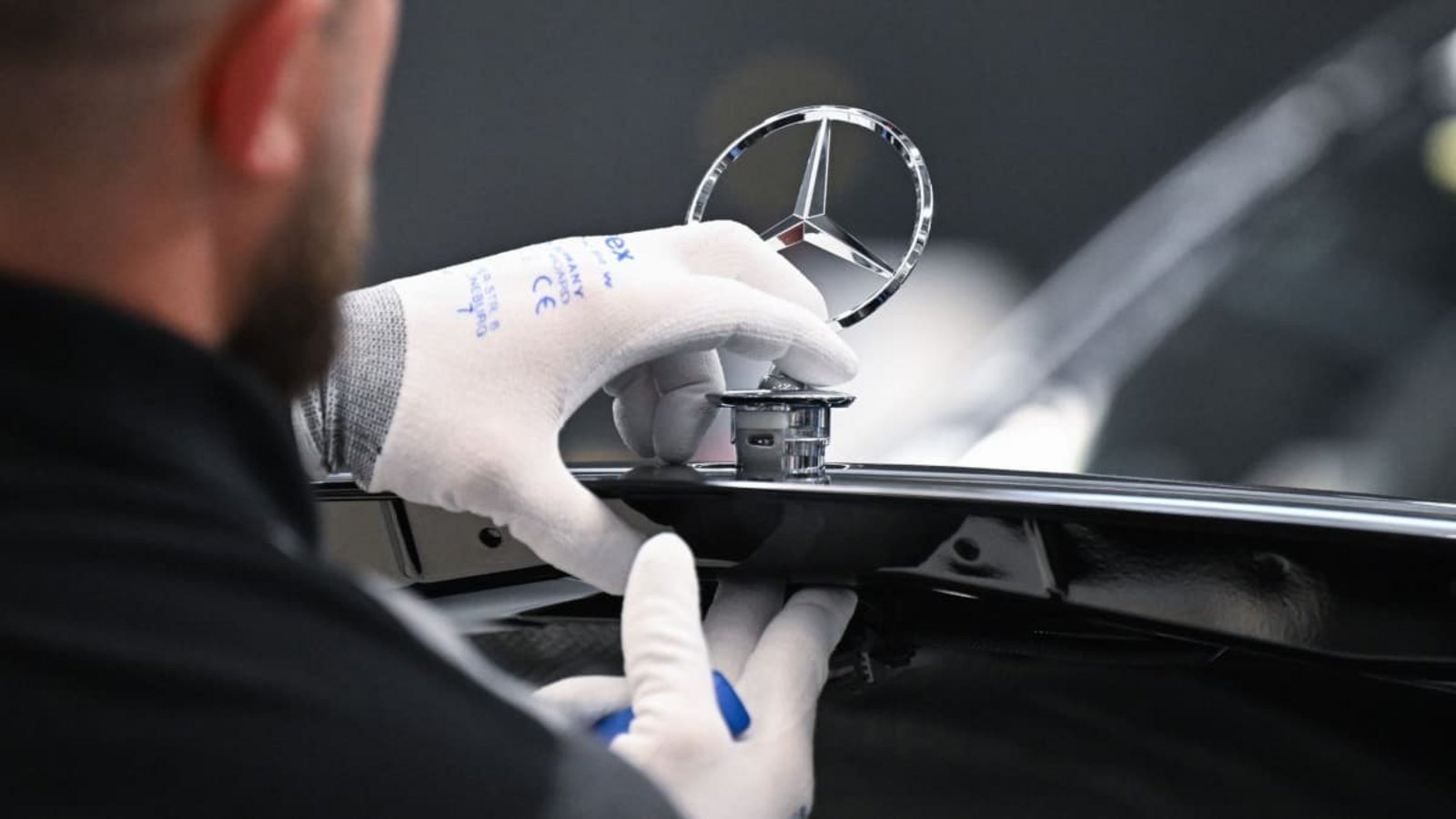 Ein Arbeiter montiert im Mercedes-Benz-Werk Sindelfingen einen Mercedes Stern auf ein Fahrzeug der S-Klasse.Bernd Weißbrod/dpa