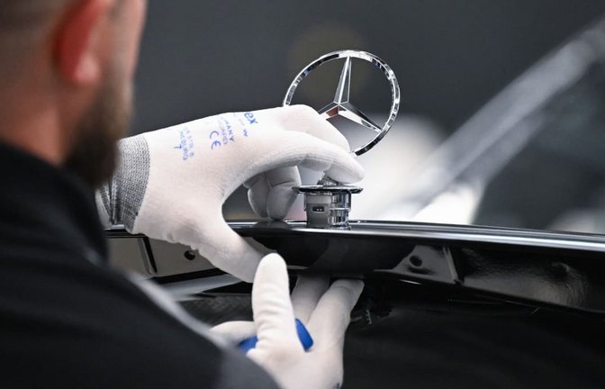 Ein Arbeiter montiert im Mercedes-Benz-Werk Sindelfingen einen Mercedes Stern auf ein Fahrzeug der S-Klasse.<span class='image-autor'>Bernd Weißbrod/dpa</span>