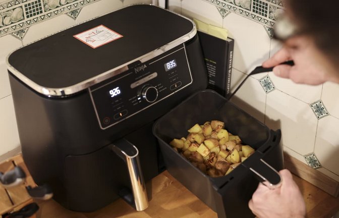 Ein Mann kocht in seiner Küchen mit einer Heißluftfritteuse (Airfryer) ein Gericht aus Kartoffelstücken und gebratenem Hühnerfleisch. (Symbolbild)<span class='image-autor'>picture alliance/dpa | Christian Charisius</span>