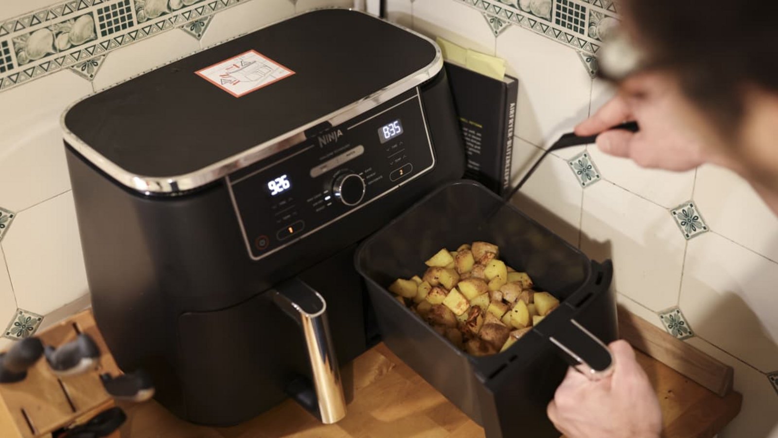 Ein Mann kocht in seiner Küchen mit einer Heißluftfritteuse (Airfryer) ein Gericht aus Kartoffelstücken und gebratenem Hühnerfleisch. (Symbolbild)picture alliance/dpa | Christian Charisius Ein Mann kocht in seiner Küchen mit einer Heißluftfritteuse (Airfryer) ein Gericht aus Kartoffelstücken und gebratenem Hühnerfleisch. (Symbolbild)picture alliance/dpa | Christian Charisius