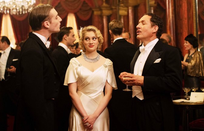 Madeline (Nadia Tereszkiewicz) stellt Monsieur Palmarède (Dany Boon, re.) ihren zukünftigen Verlobten André Bonnard (Édouard Sulpice) vor.<span class='image-autor'>Foto:  rbb/Carole Bethuel/MANDARIN ET COMPAGNIE/FOZ/GAUMONT/SCOPE PICTURES/FRANCE 2 CINEMA/PLAYTIME PRODUCTION</span>