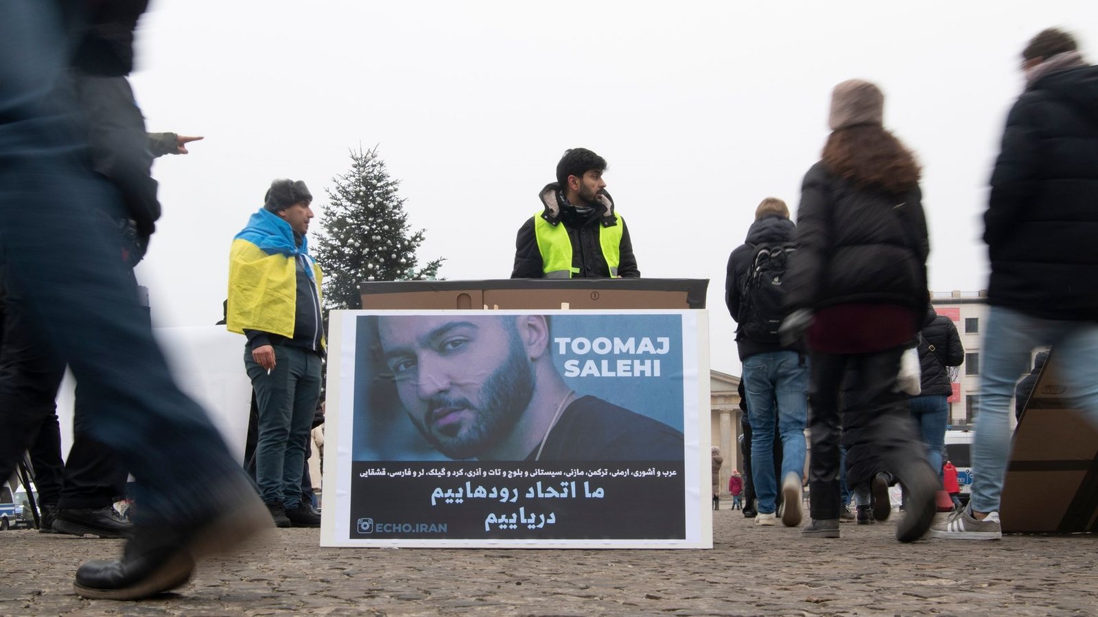 Protestaktion gegen Irans Staatsführung auf dem Pariser Platz in Berlin. Auf dem Plakat ist der Rapper Salehi zu sehen.Foto: Paul Zinken/dpa