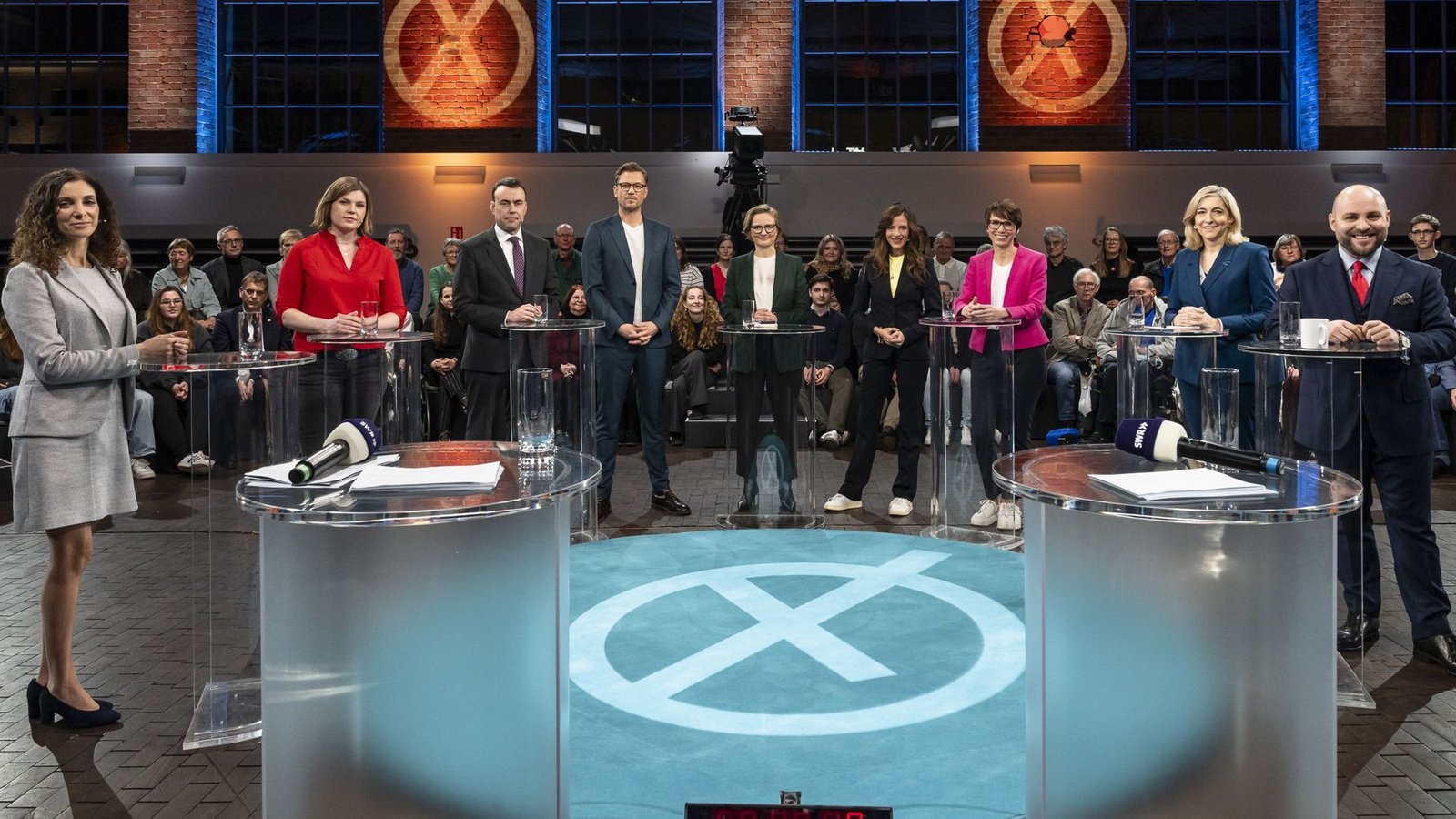 Die Gäste in der SWR-Wahlarena (von links nach rechts): Jessica Tatti (BSW), Sahra Mirow (Linke), Nils Schmid (SPD),  Nina Warken (CDU), Judith Skudelny (FDP), Franziska Brantner (Grüne) und Markus Frohnmaier (AfD). In der Mitte stehen die drei SWR-Moderatoren.Foto: SWR