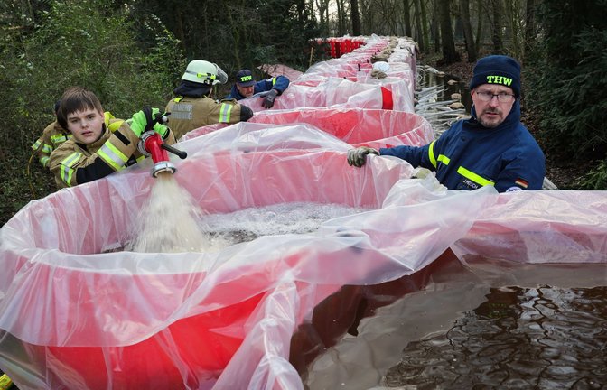 Niedersachsen, Oldenburg: Mitarbeiter von THW und der Feuerwehr Oldenburg befüllen Elemente eines mobilen Notdeichs mit Wasser. Der mobile Deich wird neben dem Parkfriedhof Bümmerstede errichtet.<span class='image-autor'>Foto: dpa/Christian Charisius</span>