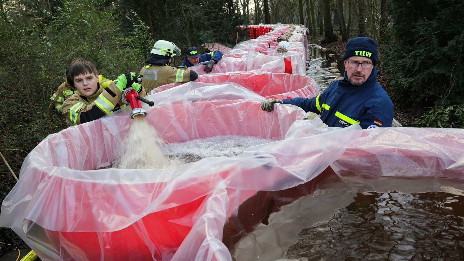 Niedersachsen, Oldenburg: Mitarbeiter von THW und der Feuerwehr Oldenburg befüllen Elemente eines mobilen Notdeichs mit Wasser. Der mobile Deich wird neben dem Parkfriedhof Bümmerstede errichtet.Foto: dpa/Christian Charisius Niedersachsen, Oldenburg: Mitarbeiter von THW und der Feuerwehr Oldenburg befüllen Elemente eines mobilen Notdeichs mit Wasser. Der mobile Deich wird neben dem Parkfriedhof Bümmerstede errichtet.Foto: dpa/Christian Charisius