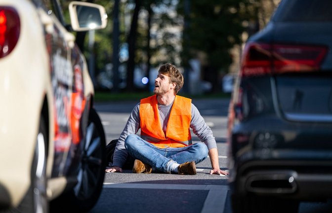 Ein Klima-Aktivist blockiert in München eine Straße.<span class='image-autor'>Foto: dpa/Lennart Preiss</span>