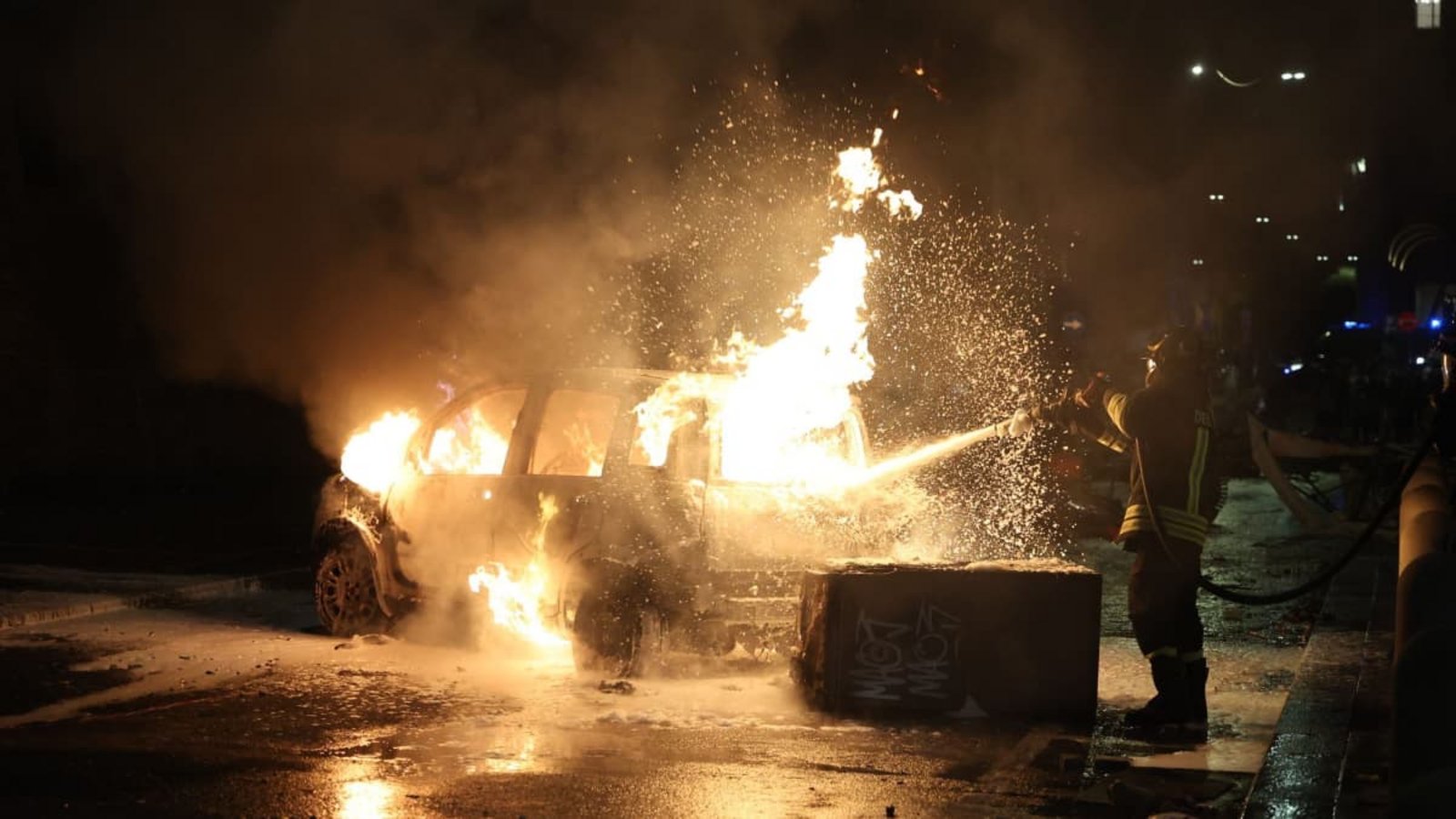 Einsatzkräfte löschen ein brennendes Auto nach Auseinandersetzungen bei Protesten in ItalienGuido Calamosca/dpa Einsatzkräfte löschen ein brennendes Auto nach Auseinandersetzungen bei Protesten in ItalienGuido Calamosca/dpa