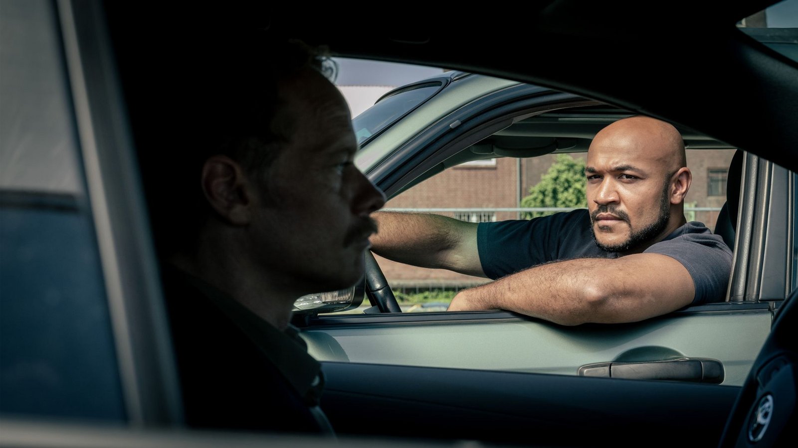 Otto Pösken (Malick Bauer, r) und Daniel Kossik (Stefan Konarske, l) unterhalten sich durchs Autofenster –  Daniel Kossik ermittelt weiter gegen Rosa Herzog und Peter Faber; Otto Pösken soll ihm undercover dabei helfen.Foto: WDR/Thomas Kost
