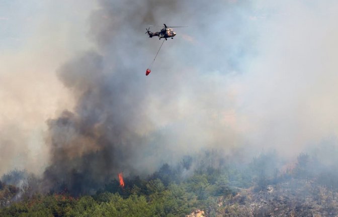 Ein Hubschrauber lässt Wasser ab, um ein Feuer in der Nähe von Izmir zu löschen. Einsatzkräfte in der Türkei kämpfen in mehreren Provinzen gegen Brände, die sich bei starken Winden ausbreiten (Archivfoto).<span class='image-autor'>Cengiz Malgir/DIA Photo via AP/dpa</span>