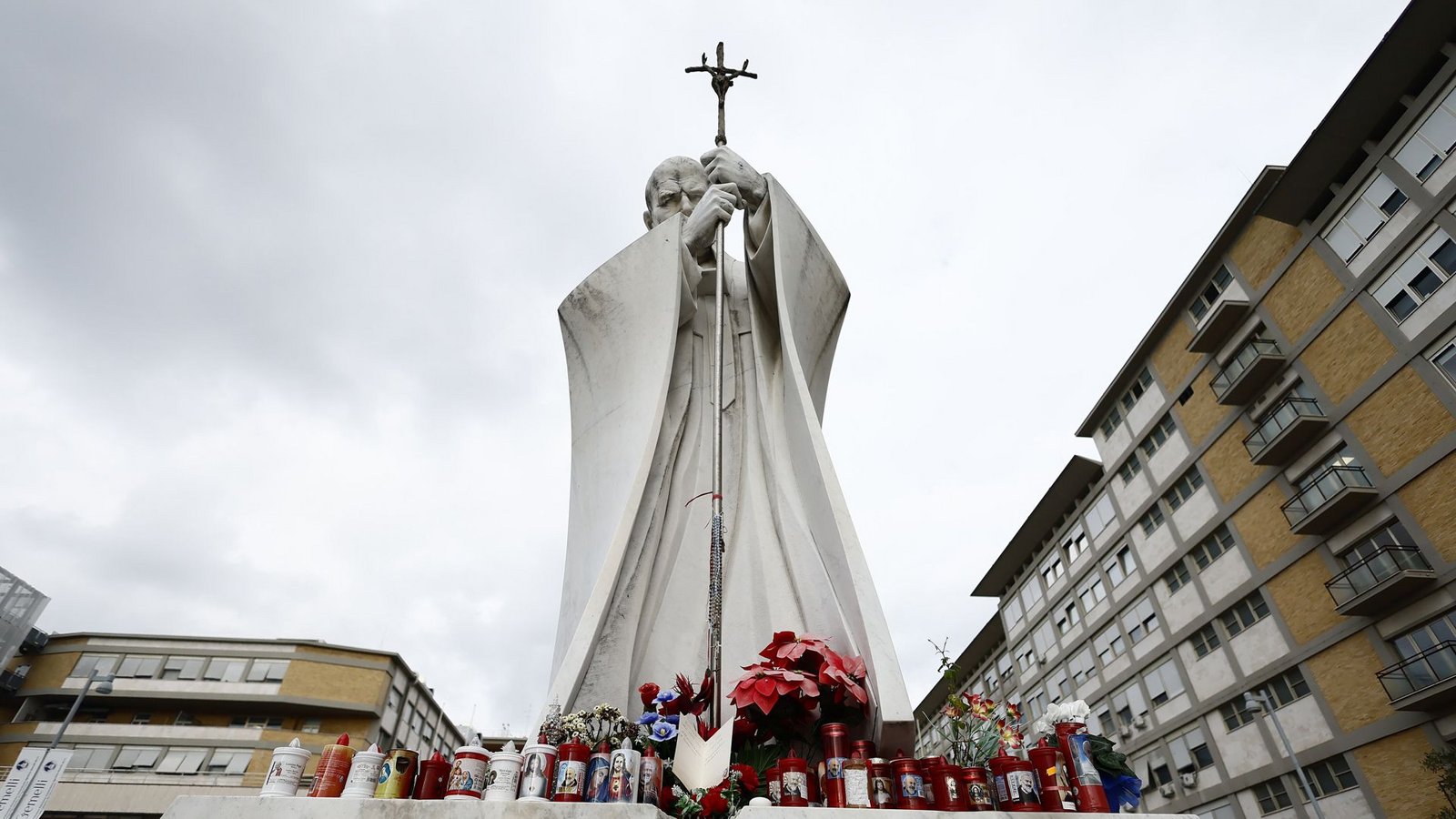 Blumen und Kerzen stehen vor einer Statue von Papst Johannes Paul II. neben der Poliklinik Agostino Gemelli in Rom, wo Papst Franziskus zur Untersuchung liegt.Foto: dpa/Cecilia Fabiano
