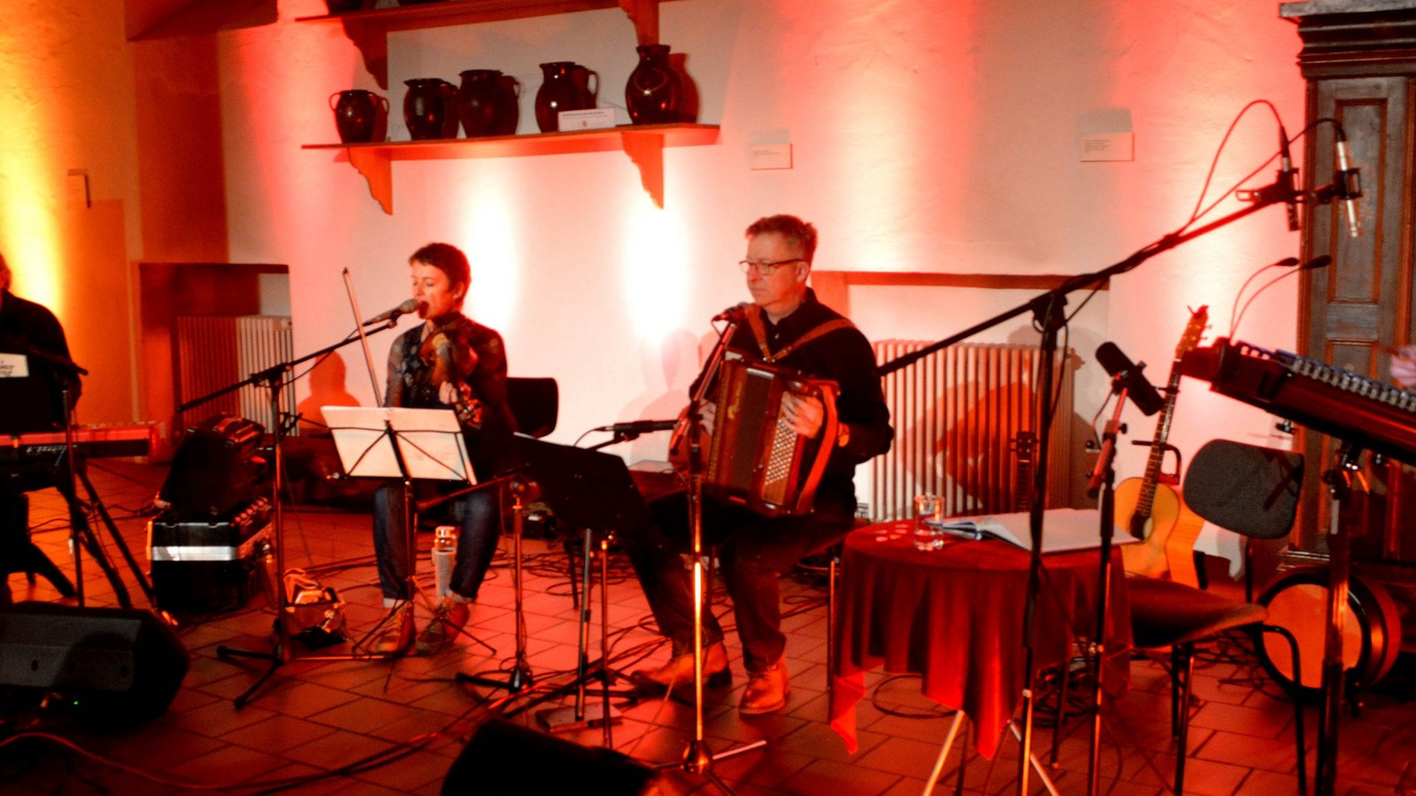 Zweimal hatte die Veranstaltung wegen Corona verschoben werden müssen. Beim dritten Anlauf am Freitag klappte es: Die Rasslerbande lud in der historischen Kelter in Mühlacker zur musikalischen Geschichtsstunde. Thema: Die als „Rassler“ bekannten Arbeiter der Pforzheimer Schmuckindustrie. „Rassler Bauer Goldschmied“ war die musikalisch-literarische Spurensuche von Sven Puchelt, Roland Bliesener, Christian Roch und Christina Sogl überschrieben, die der Pforzheimer Folkclub Prisma anlässlich des Pforzheimer Schmuckjubiläums „250 Jahre Goldstadt“ im Jahre 2017 aus gutem Grund entwickelt hatte. Als sich in Pforzheim die Schmuckindustrie entwickelte, war das auch die Geburtsstunde der „Rassler“ gewesen. Im Jahr 1850 setzte der Zustrom der Landbevölkerung ein. Um 1900 seien, wie am Abend mitgeteilt wurde, rund 24 000 Menschen in 900 Fabriken beschäftigt gewesen. Die Hälfte von ihnen waren „Rassler“. Diese „Rassler“ waren Bauern aus den umliegenden Dörfern, die jeden Morgen zur Arbeit in die Stadt wanderten. Ihren Namen bekamen sie vom Klappern der mit Eisen beschlagenen Schuhe auf dem Kopfsteinpflaster. Oder war es etwa das Klappern der Kannen, in denen sie ihr Essen mitbrachten? Oder gar die Verballhornung des Begriffs Raser? Diese Frage blieb am Freitagabend zwar unbeantwortet, auf ganz viele andere aber gab das Quartett singend und sprechend Auskunft. Das Quartett präsentierte eine gelungene Mischung aus Texten und Liedern. Da keine traditionellen Melodien aus Pforzheim und den umliegenden Gemeinden überliefert sind, hatten die Musiker historische baden-württembergische Tänze und Volkslieder ausgesucht. Letztere habe man etwas moderner arrangiert, so Christian Roch, Vorsitzender des Vereins Folkclub Prisma. Unter anderem hatte man das Gedicht „O Schwarwald, o Heimat“ von Ludwig Auerbach neu vertont. Roch wies zudem darauf hin, dass die „Rassler“ nicht nur aus der direkten Umgebung Pforzheims kamen. Auch aus dem Raum Mühlacker sei man zur Arbeit nach Pforzheim gegangen – allerdings nicht zu Fuß sondern nach dem Bau der Eisenbahnlinie mit der Bahn. Kurzweilig und äußerst informativ gaben er und die übrige Rasslerbande Einblicke in die Lebensart der Goldschmiedsbauern, die ihren Lebensunterhalt in der Schmuckindustrie, aber auch in der Landwirtschaft verdienten. Gespartes Geld floss in die eigene Scholle, so Puchelt. Foto: Stahlfeld