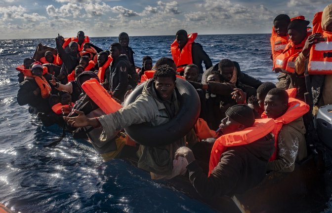 Mehrere Migranten sitzen in einem Boot im Mittelmeer, während Rettungskräfte versuchen ihnen zu helfen.<span class='image-autor'>Foto: Antonio Sempere/Europa Press/dpa</span>