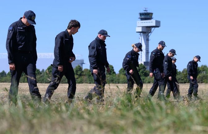 Polizisten suchen nach dem Vorfall am Flughafen Leipzig/Halle die Umgebung ab. Auf einem angrenzenden Feld wurden sie offenbar fündig.<span class='image-autor'>Hendrik Schmidt/dpa</span>