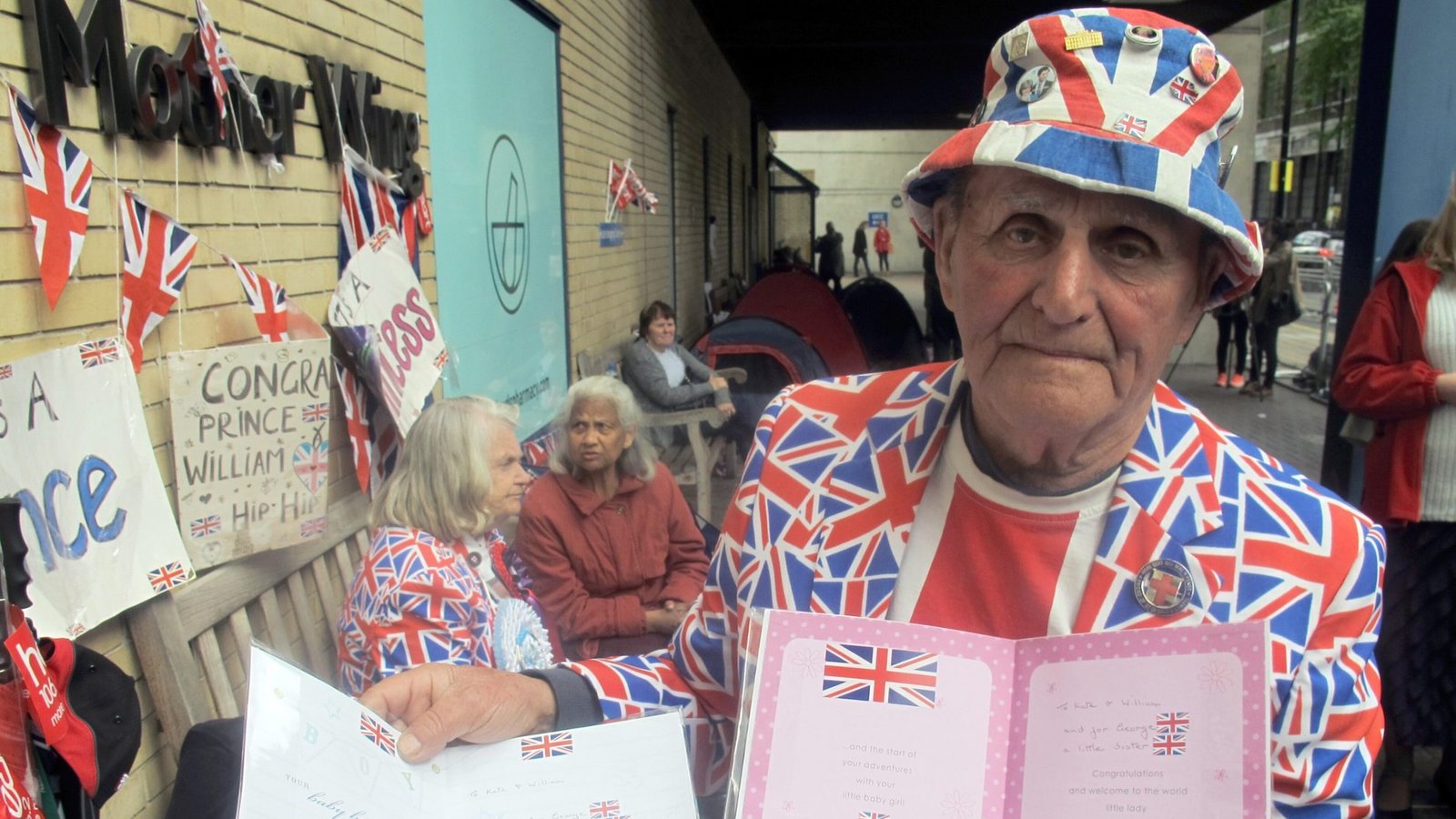 Der Brite Terry Hutt zeigt am 30.04.2015 - seinem 80. Geburtstag - vor dem St. Mary's Hospital in London (Großbritannien) zwei Karten für den erwarteten Nachwuchs im britischen Königshaus: eine für einen Jungen und eine für ein Mädchen. In der Klinik wird Herzogin Kate ihr zweites Kind zur Welt bringen.Foto: picture alliance / dpa | Britta Schultejans