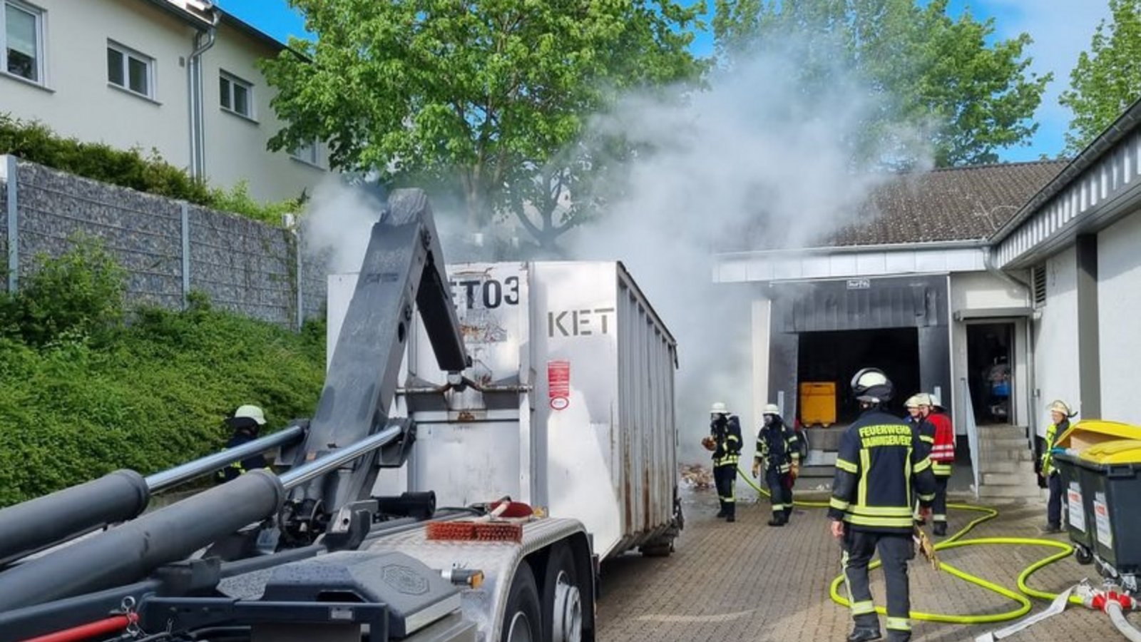 Der brennende Container wird vom Gebäude weggezogen, um zu verhindern, dass sich das Feuer ausbreitet.  Foto: FW Vaihingen